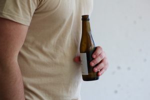 Einsamkeit und Sucht: Man hält Alkoholflasche in der Hand